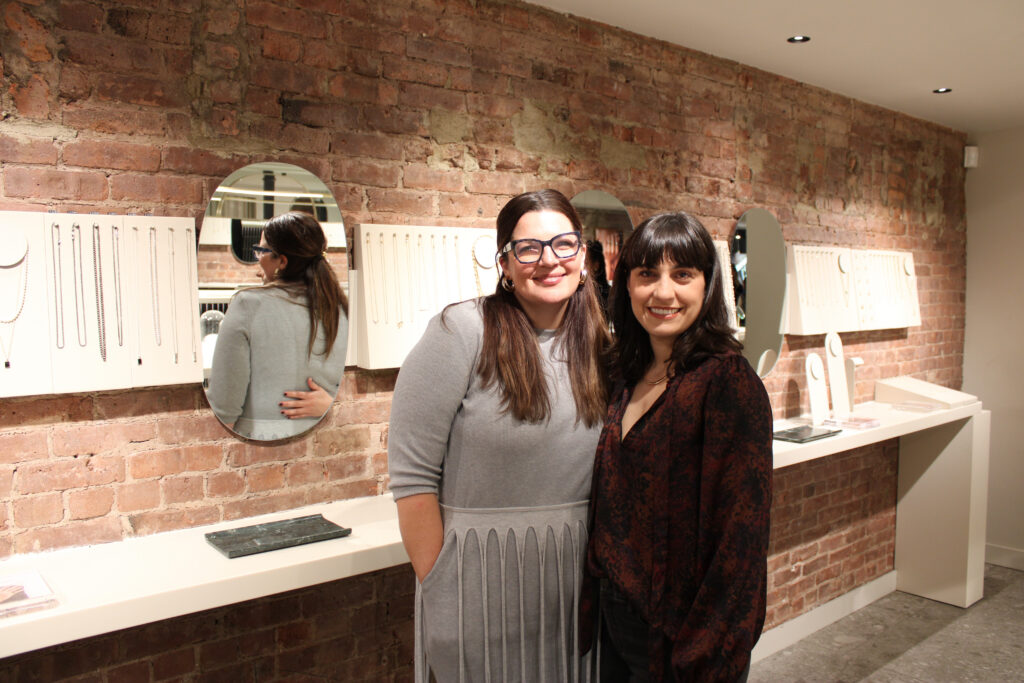 Kate MacCabe founder of Flywheel Strategy and Lauren Mecca founder of Tech/ish smiling and posing together inside a well-lit jewelry store during an event.
